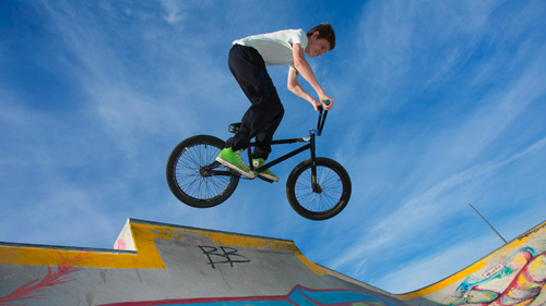 A boy is cycling high above a skateboard ramp